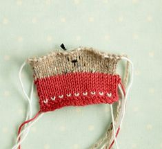 a red and white knitted object sitting on top of a polka dot tablecloth