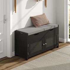 a black storage bench with two brown pillows on it and a white door in the background