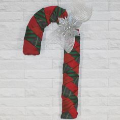 a red and green christmas candy cane hanging on a brick wall