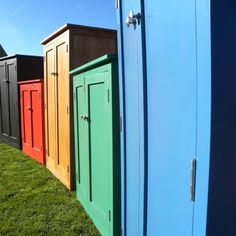 there are many different colored doors on this fenced in area that looks like they have been built into the grass