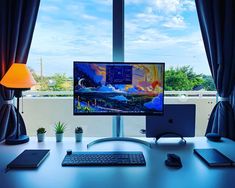 a desktop computer sitting on top of a desk next to a lamp and window sill