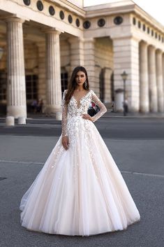 a woman in a wedding dress standing on the street with her hands on her hips