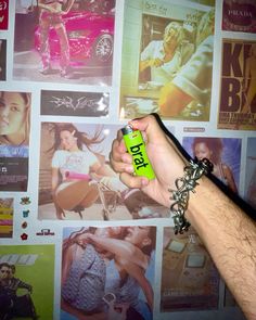 a person holding a lighter in front of a wall covered with pictures and posters on it