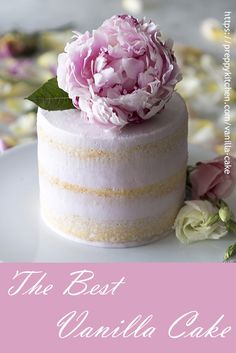 a white cake with pink flowers on top and petals around the edges, sitting on a plate