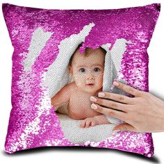 a pink sequin pillow with a baby's face in the center and hands holding it