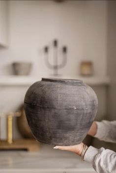 a woman is holding a large vase in her hand while she holds it up to the camera