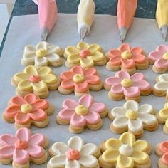 decorated cookies are on a baking sheet with icing and pink, yellow, and white flowers