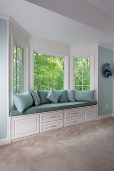 a living room filled with lots of furniture next to a window covered in blue pillows