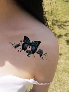 the back of a woman's shoulder with a blue butterfly and flowers on it