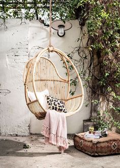 a hammock chair hanging from a tree in front of a wall with vines