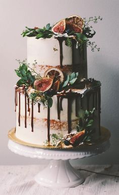 a three tiered cake decorated with figs and greenery