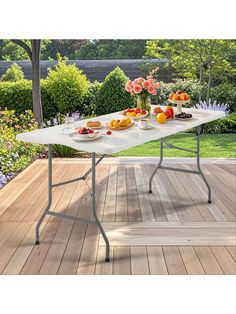 an outdoor table with fruit on it and flowers in vases next to the table