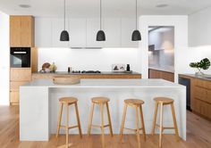 an open concept kitchen and living room with wood flooring, white countertops and bar stools