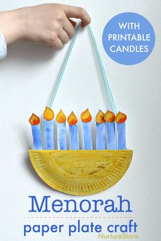 a hand holding a paper plate that has candles on it with the words menorah in front of it