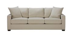 a beige couch with four pillows on the back and one arm folded up in front