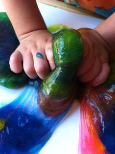 a close up of a child's hand holding a piece of art with paint on it