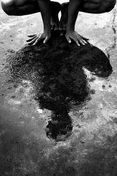 a woman kneeling down on top of a puddle