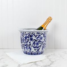 a bottle of champagne in a blue and white porcelain container on a marble countertop