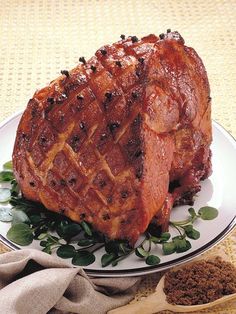 a large piece of meat sitting on top of a white plate next to a wooden spoon