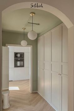 an archway leading into a kitchen with white cabinets and cupboards on either side of the room