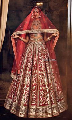 a woman in a red and gold bridal gown is standing with her hands on her hips