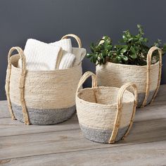 three woven baskets with plants in them on a wooden table