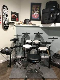 there is a drum set in the room with other musical equipment on the wall behind it