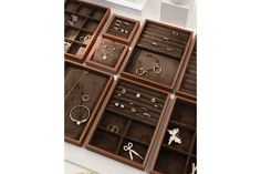 many different types of jewelry are displayed in wooden boxes