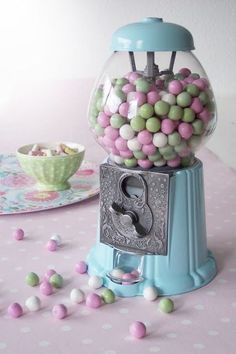 a gum ball machine on a pink table with white and blue polka dotes around it