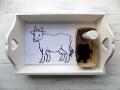 a tray with a cow drawn on it next to some black and white items in the tray