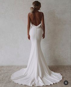 the back of a woman in a white wedding dress, with her hands on her hips