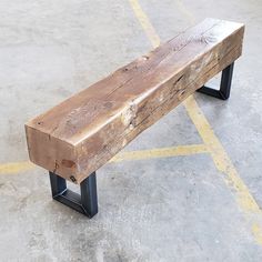 a wooden bench sitting on top of a parking lot next to a yellow and black line