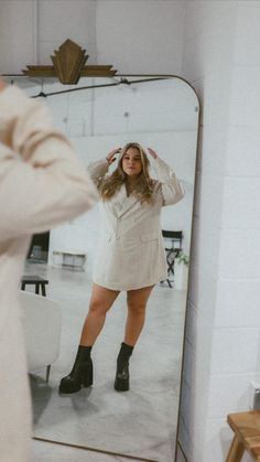 a woman taking a selfie in front of a mirror with her hand on her hip