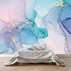 a bed in front of a large wall mural with blue and pink paint on it