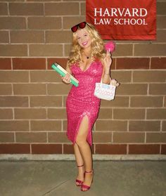 a woman in a pink dress is holding a flower and some shopping bags while standing next to a brick wall