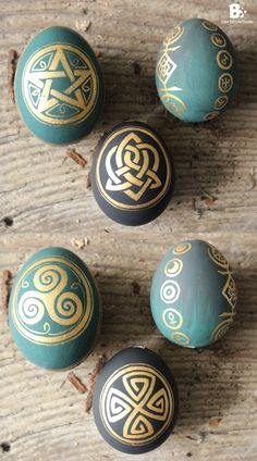 four decorative painted eggs sitting on top of a wooden table