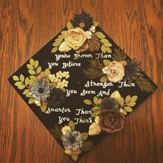 a graduation cap decorated with flowers on top of a wooden table