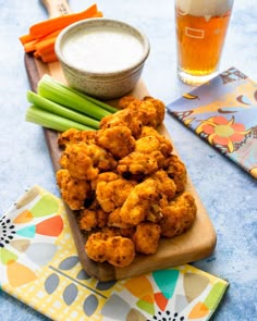 a wooden cutting board topped with tater tots and celery sticks