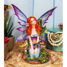 a fairy figurine sitting on top of a table next to a potted plant