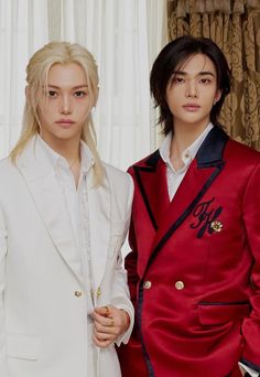 two young men standing next to each other in front of a white curtain with curtains behind them