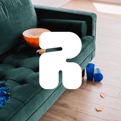 a green couch sitting on top of a hard wood floor next to a blue cup