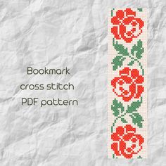 a cross stitch bookmark with red roses and green leaves on it, next to a white paper background