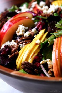 a salad with apples, walnuts, and other vegetables in a bowl on a table