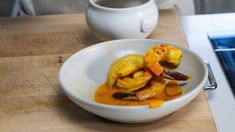 a white bowl filled with food on top of a wooden table