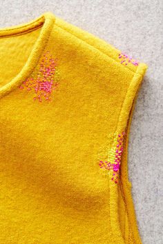 a close up of a yellow shirt with pink sprinkles on the side