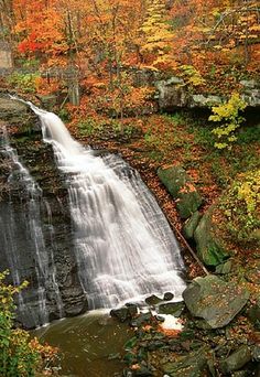 a waterfall surrounded by trees in the fall