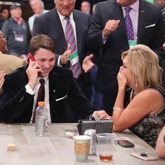 a group of people sitting around a table talking on cell phones