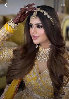 a woman in a yellow dress with long brown hair and jewelry on her head is posing for the camera