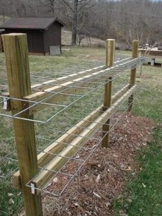 a wooden fence with wire around it on the grass and trees in the back ground