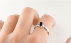 "A simple ring with a bright purple natural amethyst cabochon that is bezel set in sterling silver. The amethyst, mined in Brazil, is 5mm round (about 1/4\" inch). A minimal and elegant design durable enough for everyday wear. The sterling silver is hypoallergenic nickel free. Size adjustments are available upon request- just message us! Our jewelry was designed and made by Jan Palombo of Great Falls Metalworks who has been making jewelry in the USA since 1968. The collection in this shop is of Dainty Adjustable Amethyst Ring, Gift Amethyst Ring With Bezel Setting In Sterling Silver, Minimalist Silver Amethyst Ring, Adjustable Purple Sterling Silver Birthstone Ring, Modern Amethyst Ring With Bezel Setting As Gift, Minimalist Amethyst Gemstone Ring, Modern Round Amethyst Ring, Purple Gemstone Stackable Rings In Sterling Silver, Sterling Silver Cabochon Amethyst Ring